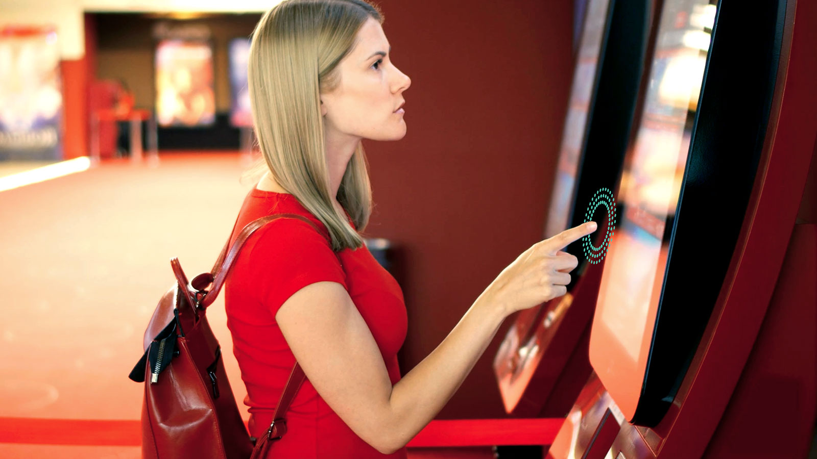 Lady wearing red top using a touchless kiosk